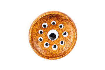 Small googley eyes surround a large single eye in a wooden bowl