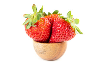 Three ripe strawberries sitting inside a wooden bowl side view
