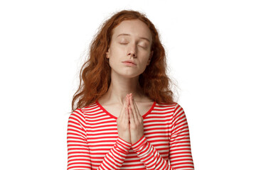 Religious young redhead woman praying to god, pressing palms together