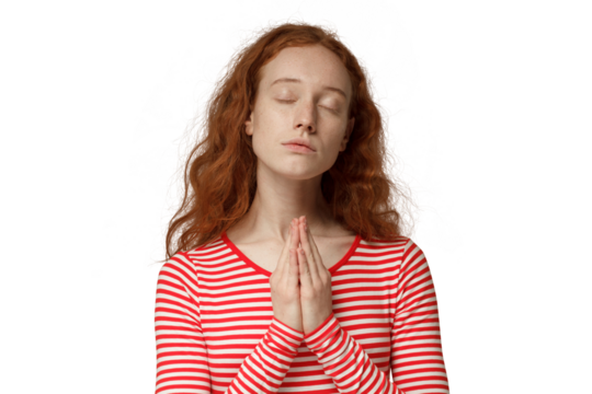 Religious young redhead woman praying to god, pressing palms together