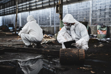 Workers in Protective Suits Checking Chemicals in Old Factory. Protecting Against Hazards and...