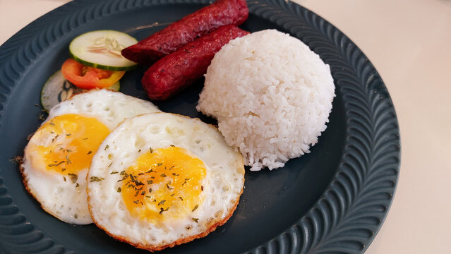 Close up to a plate of fried eggs, longganisa and rice, typical authentic daily pinoy breakfast food in the Philippines