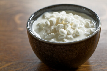 Grainy cottage cheese in a bowl. Fresh European cuisine ingredient.