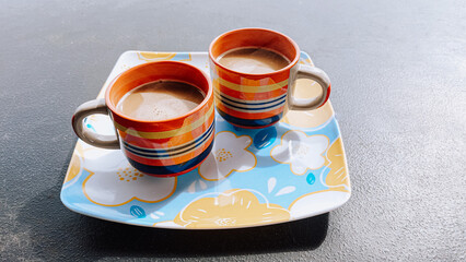 Coffee served in two colorful bohemian styled cups, bubbly and carefree coffee time