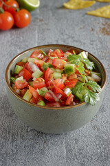 Pico de Gallo salsa in a bowl. Traditional Mexican cuisine dish with tomato, cucumber, onion and fresh coriander.