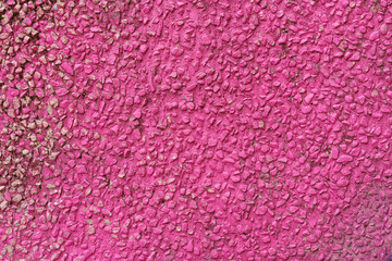 The texture of a wall made of fine gravel painted red.