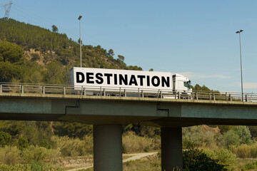 A truck is driving across the bridge, with the inscription on the trailer - Destination.
