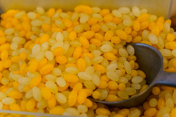 There are yellow and orange gummies and a scoop on the counter.