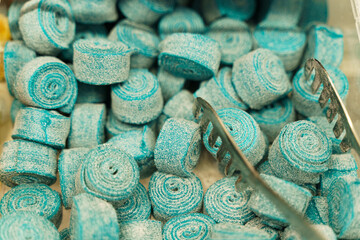 There are candies on the counter - blue chewing marmalade on a roll and tongs.