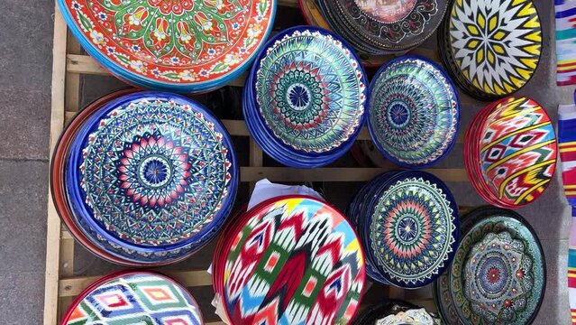 Uzbek national ceramic tableware in Tashkent - June 29, 2023: Goods at the Oriental Bazaar in Uzbekistan. Chorsu Market. Plates, teapots, cups. Painting with floral ornament. 4K