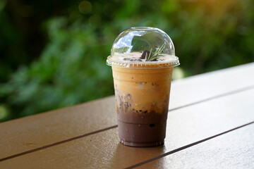 A glass of iced cocoa Thai tea on a wooden table in a coffee shop. It is a drink that is a mixture of cocoa powder and tea. The flavor is intense, delicious and refreshing to drink.