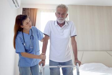 Obraz premium Female nurse or doctor helping elderly patient man lean to walk with orthopedic walker, patient practice walking inside house with physiotherapist, nursing senior people at house, medical health care.