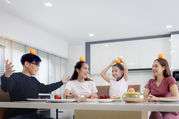 Happy family has meal in dining room. Parents, daughter aunt sitting around dining table and having...