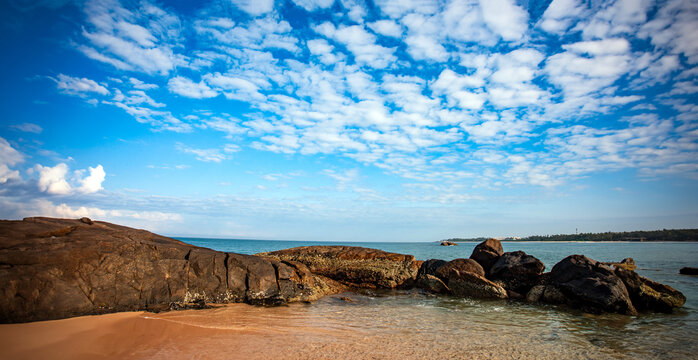 sea and rocks with white clouds in the blue sky of southern Sri Lanka beach. 