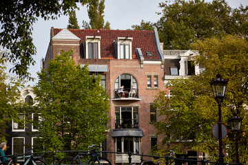 A nice building with a cute balconies and green trees in front of the house, selective focus