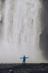 A man is standing on a cliff and watching the big waterfall in nature in Iceland.