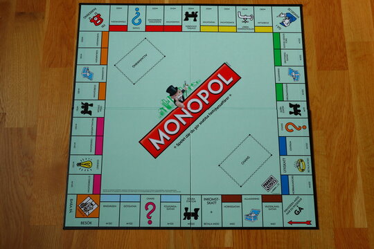 One clear and empty monopoly game board. No pieces, tokens, cards, streets, money, houses, hotels or dices. Swedish text. Aerial view. Wooden background.