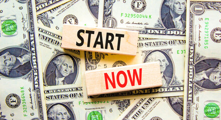 Start now symbol. Concept words Start now on beautiful wooden block. Beautiful background from dollar bills. Dollar bills. Business marketing, motivational start now concept. Copy space.
