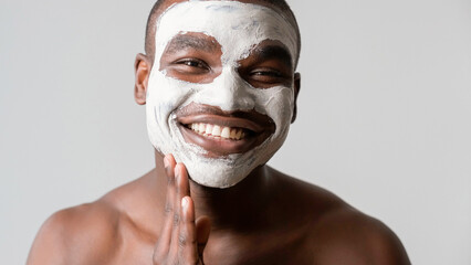 Man cosmetic. Facial mask. Confident satisfied guy enjoying applying face skin pore cleaning white...
