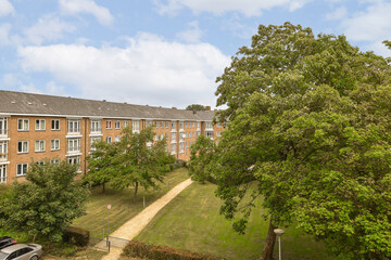 Fototapeta premium an apartment complex with trees in the foreground and cars parked on the side of the road, taken from above