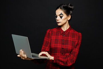 Young IT woman with Halloween makeup face art mask wears clown costume red dress work hold use...