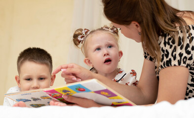 Family concept. Reading books. Mom, son and daughter are having fun reading books and spending...