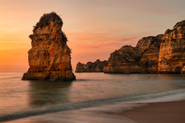 Scenic view of a rocky coastline against the sea at sunset (do camilo beach, algarve, portugal)