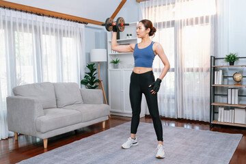 Fototapeta na wymiar Vigorous energetic woman doing dumbbell weight lifting exercise at home. Young athletic asian woman strength and endurance training session as home workout routine.