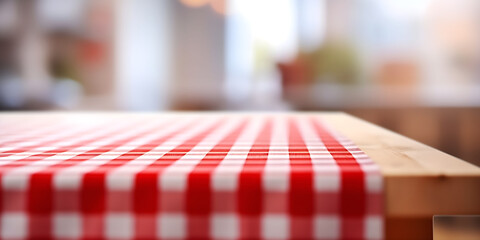 Table with red and white checkered tablecloth, blurred kitchen background. Space for product, food, brand, advertising.