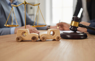 Soft focus closeup two little small wooden toy cars that have hit each other standing on office...