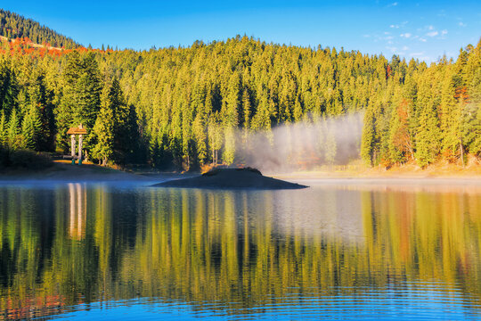 sunny landscape with lake in autumn. fog above the water surface. sky and trees reflection. sunny weather