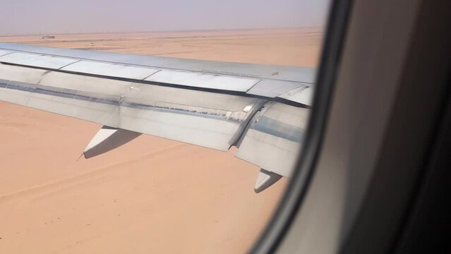 Airplane approaching and landing at Hurghada airport in the Egyptian desert, captured from the left window