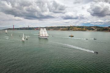 Aerial drone view of tall ships with sails sailing in Tagus river towards the Atlantic ocean in...