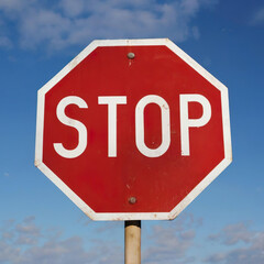 stop sign on blue sky background, white letters on red traffic sign.