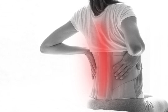 Woman with a corset on her back to support her back from pain in the back and spine, Medical concept, spinal support, wearing a brace at home