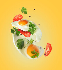 Two fried eggs with tomatoes and parsley in the air on a yellow background