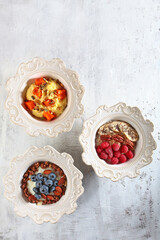 Set of bowls with porridge and berries in assortment on light background. View from above. Healthy food.