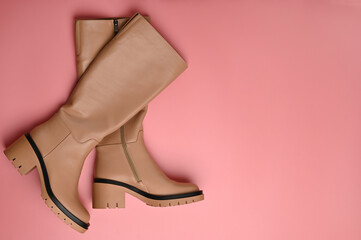 Female leather high boots on pink background