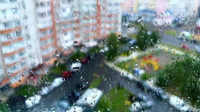 Rainy day from the window of high-rise building. Window covered with drops of water.