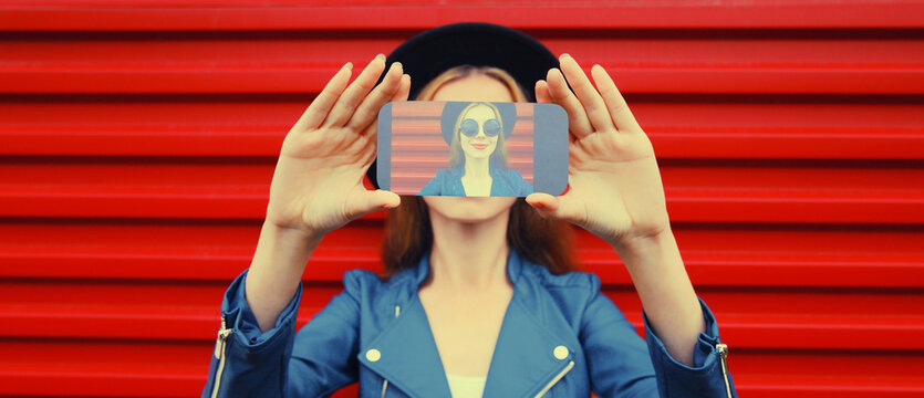 Close up of young woman stretching her hands taking selfie on smartphone on red background