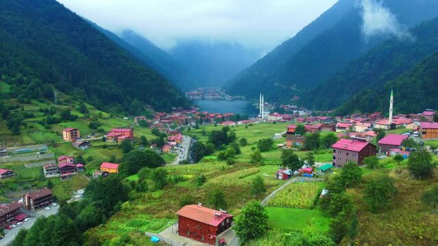 Aerial view to Uzungol lake natural lake in mountain in city of Trabzon Turkey. Aerial drone flying over large mountain forest hill, revealing beautiful lake and mosque in village on cloudy day.