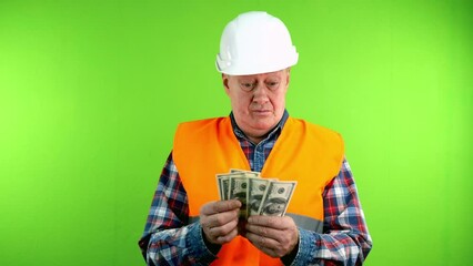 Senior builder in hardhat with pleasure counts money from construction works.