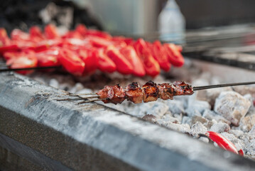 Turkish traditional meat called 'ciger' made by liver on a bbq with red tomatoes, close up, outdoor...