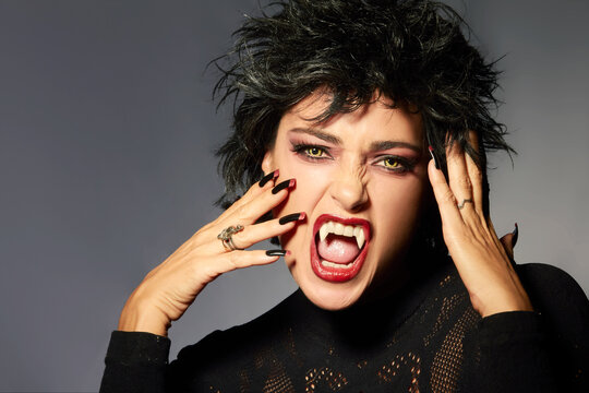 Furious expression: Halloween fantasy portrait of young adult with trendy makeup and wolf lenses. With copyspace.
