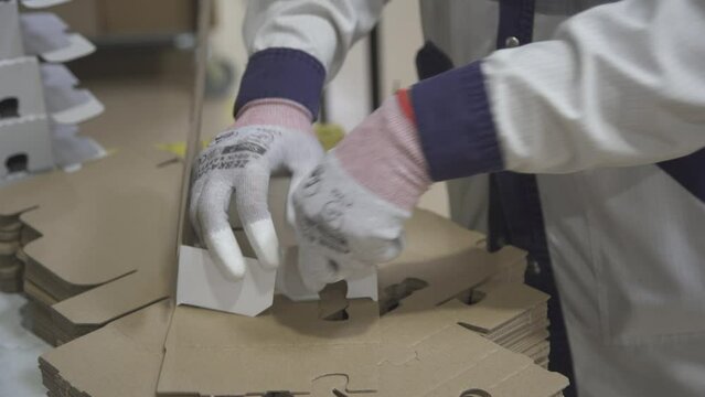 Manual assembly of a cardboard box at the factory. Production of cardboard boxes.