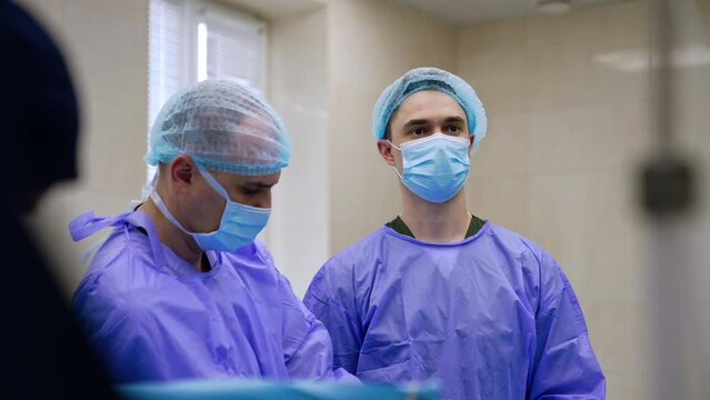 Mid-aged male surgeons working in operational room. Doctor look focused on the monitor.