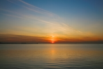 Fototapeta na wymiar Evening seascape: Setting sun over a calm sea surface
