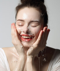 Young woman washing her face with cleanser.	