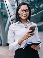 Cheerful woman browsing smartphone on street