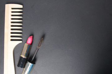 A wooden lipstick and mascara comb on a black background with space for text and copy space....